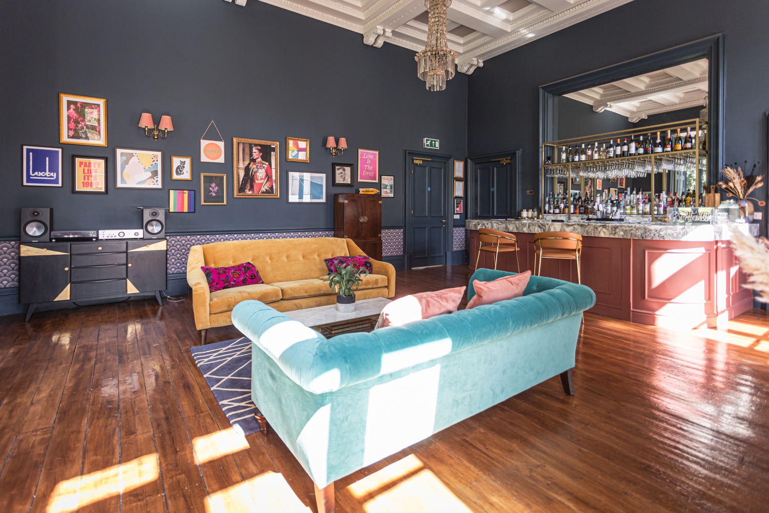 The art deco lounge & bar at Netherbyres House, with dark blue walls, modern art and brightly coloured sofas